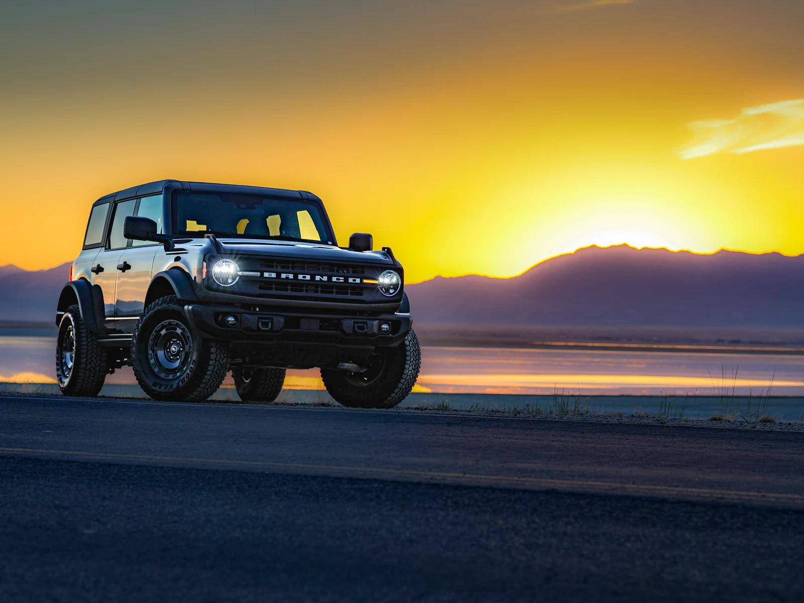 Ford Bronco parked at sunset beside Antelope Island, photographed with a Canon EOS R8.