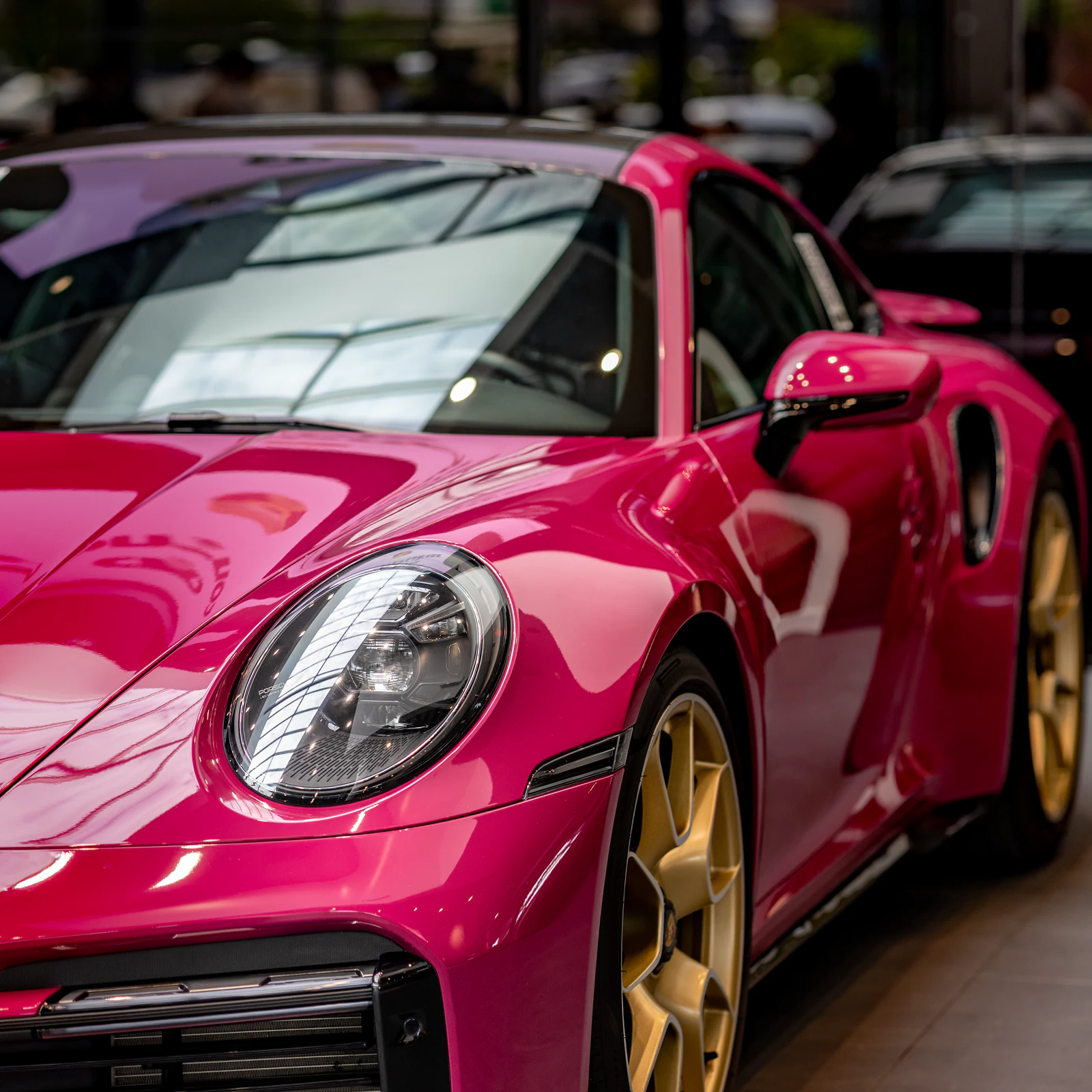 Canon EOS R8 detail photograph of a pink Porsche 911 with gold wheels.