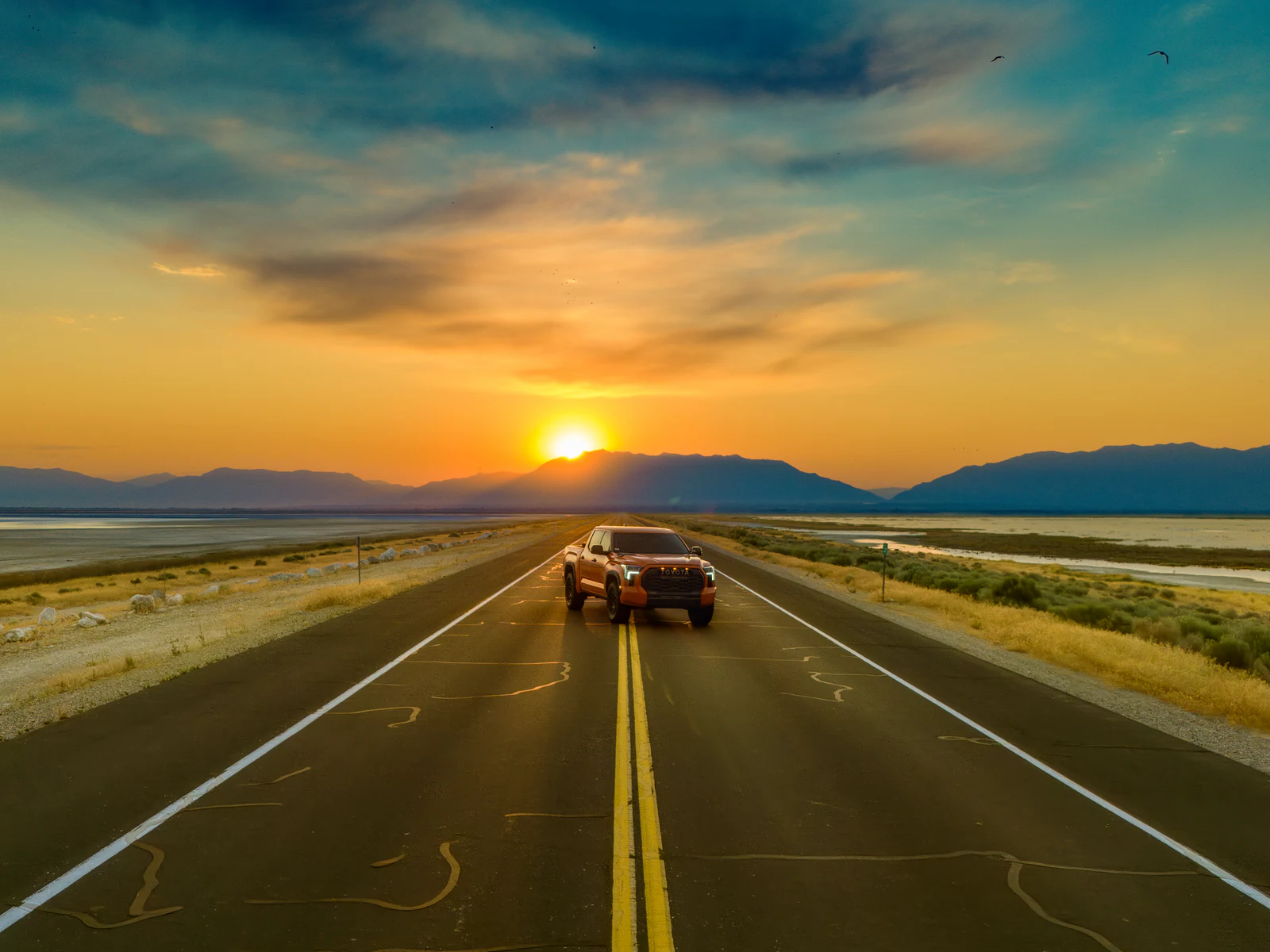 Aerial DJI photograph of Drew's former orange Toyota Tundra centered on the Antelope Island Causeway at sunset.